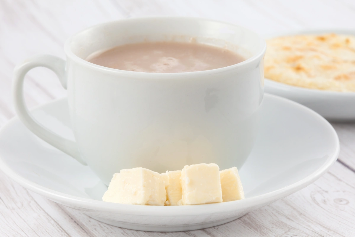 Taza de chocolate caliente con queso y una arepa, desayuno en colombia