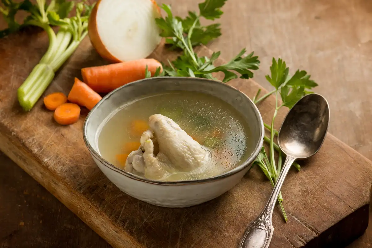 Sopa de pollo sin ingredientes sobre tabla de cortar