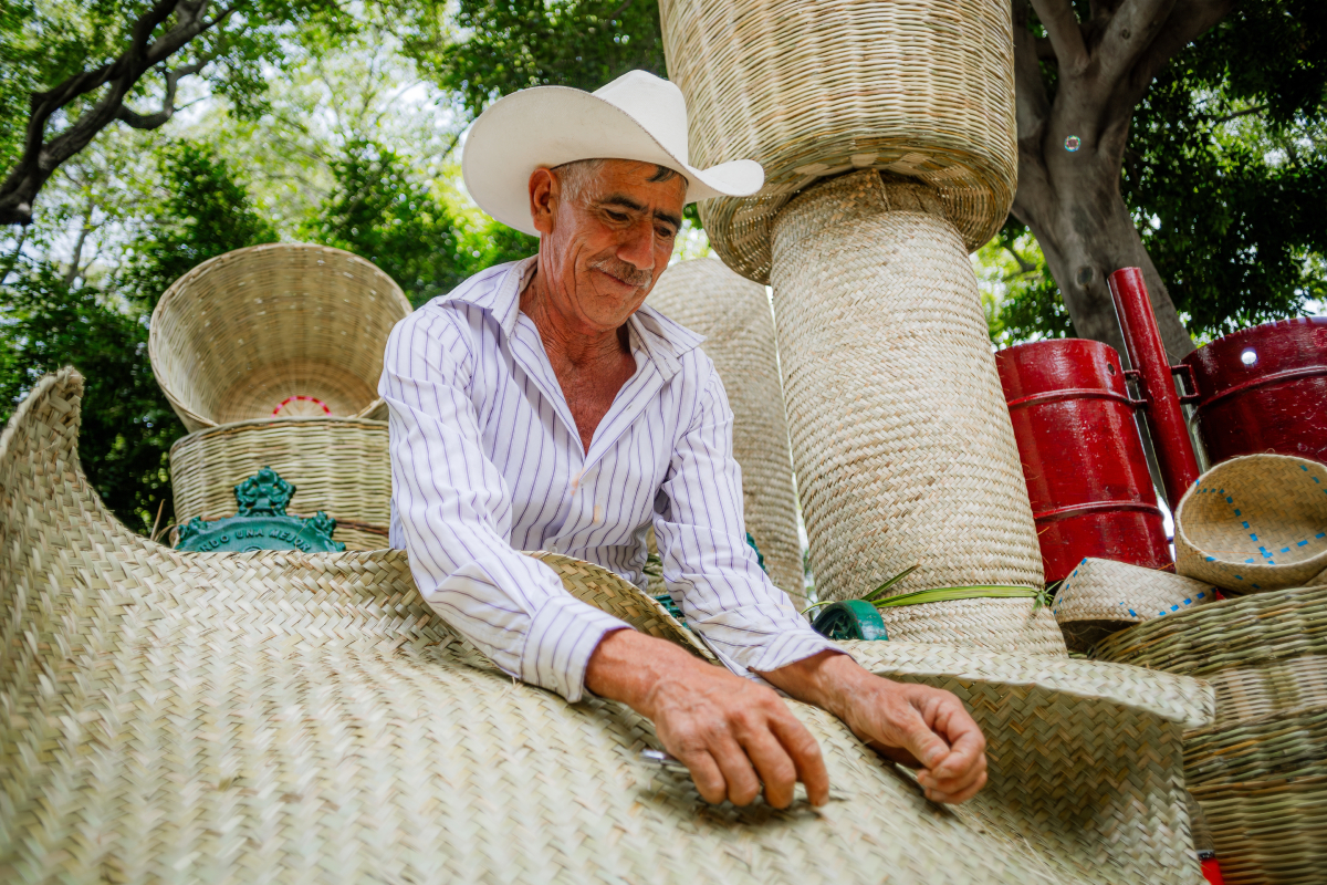 Artesano tejiendo palma para la elaboración de canasto.