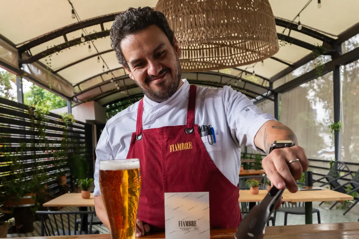 Un hombre sostiene unas pinzas para agarrar salchichas