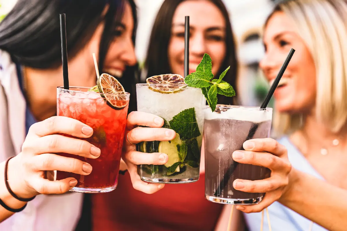 Tres chicas jóvenes toman mojito y copan vidrio juntos en el pub disfrutando de una hora feliz en la fiesta de verano- concepto de estilo de vida
