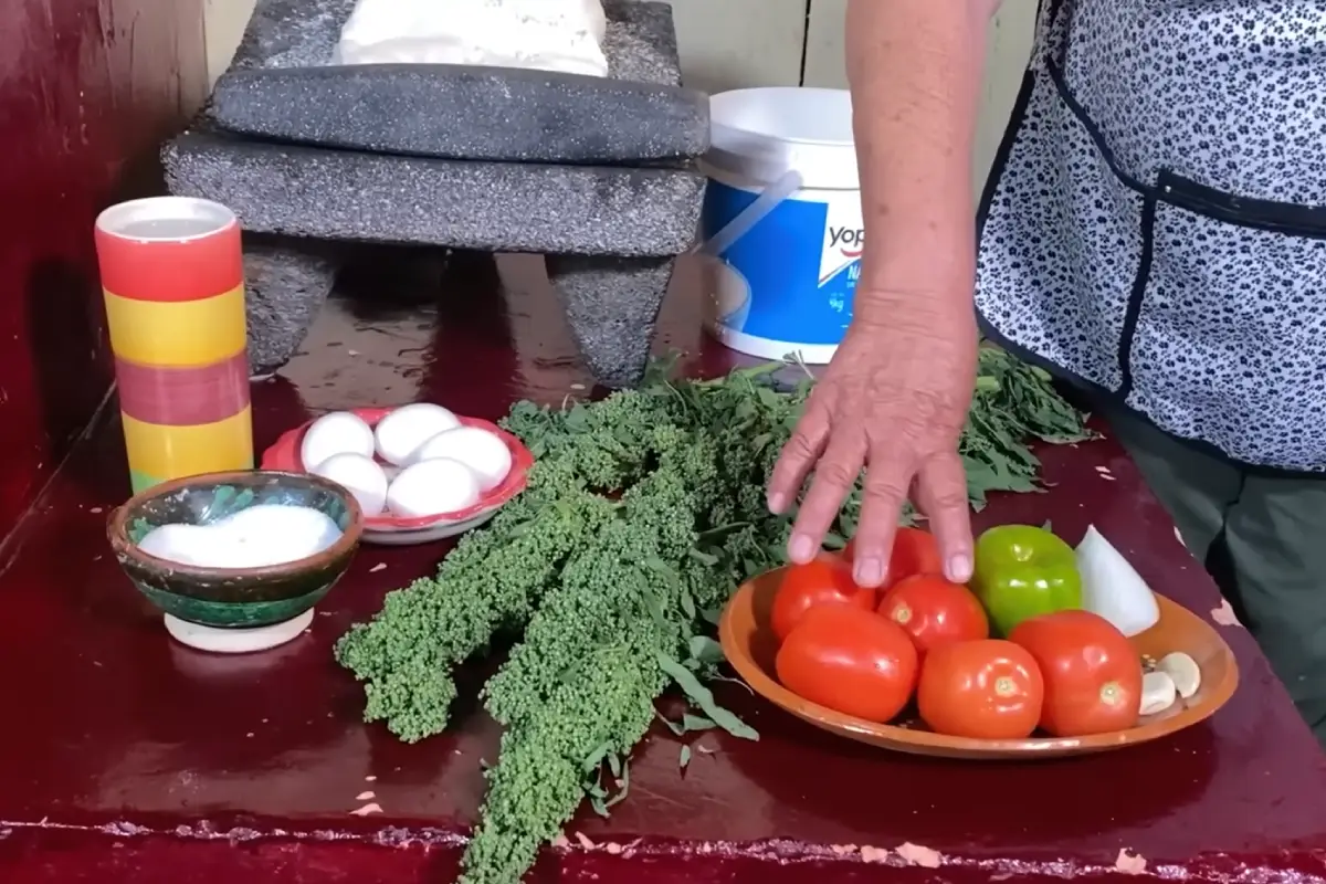 En una mesa hay jitomates, cebolla, chiles y huanzontle