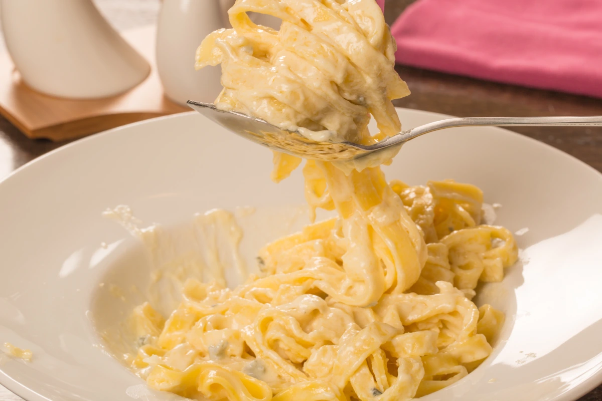 En un plato blanco está servida pasta preparada con quesos.
