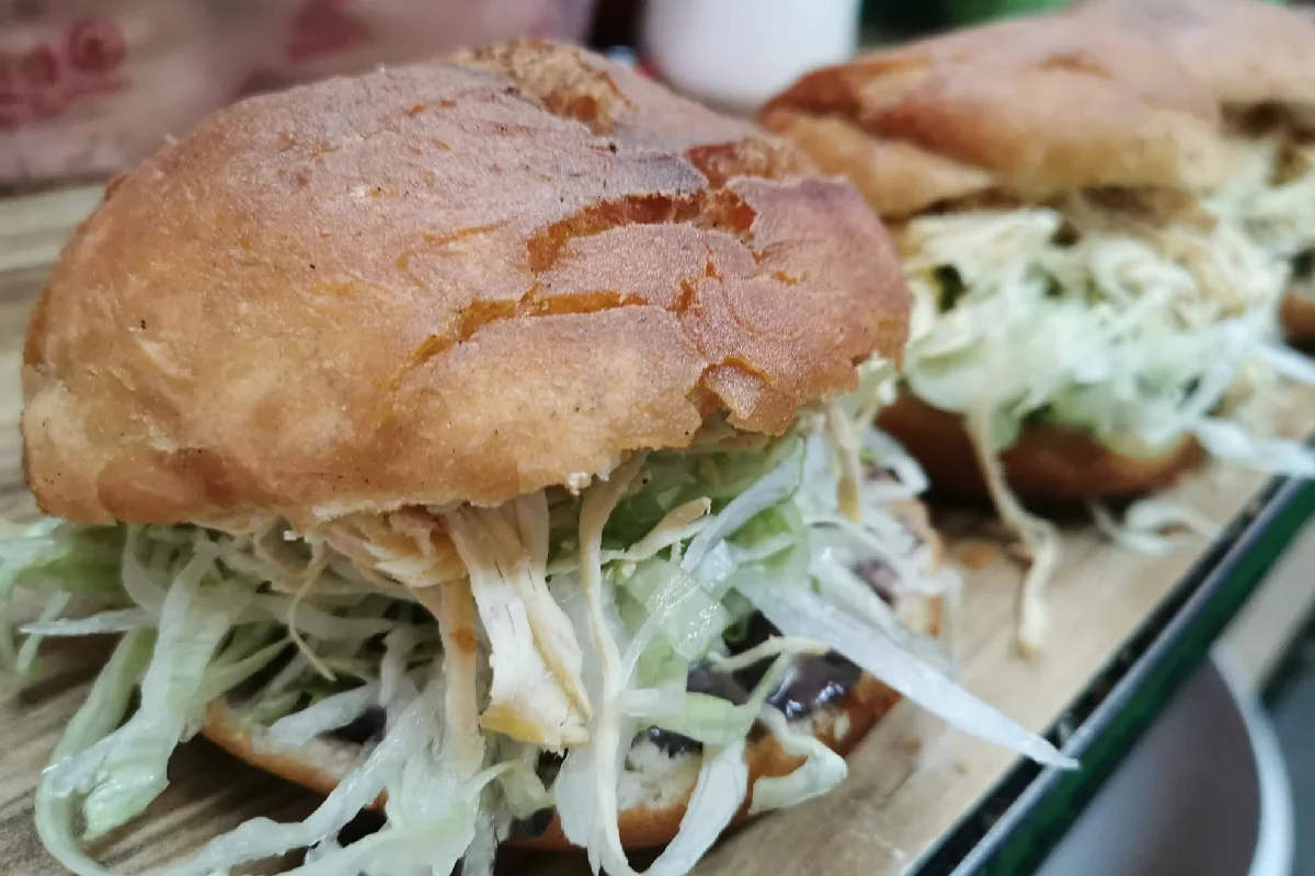 Sobre una tabla están exhibidas una especie de tortas rellenas de pollo y lechuga