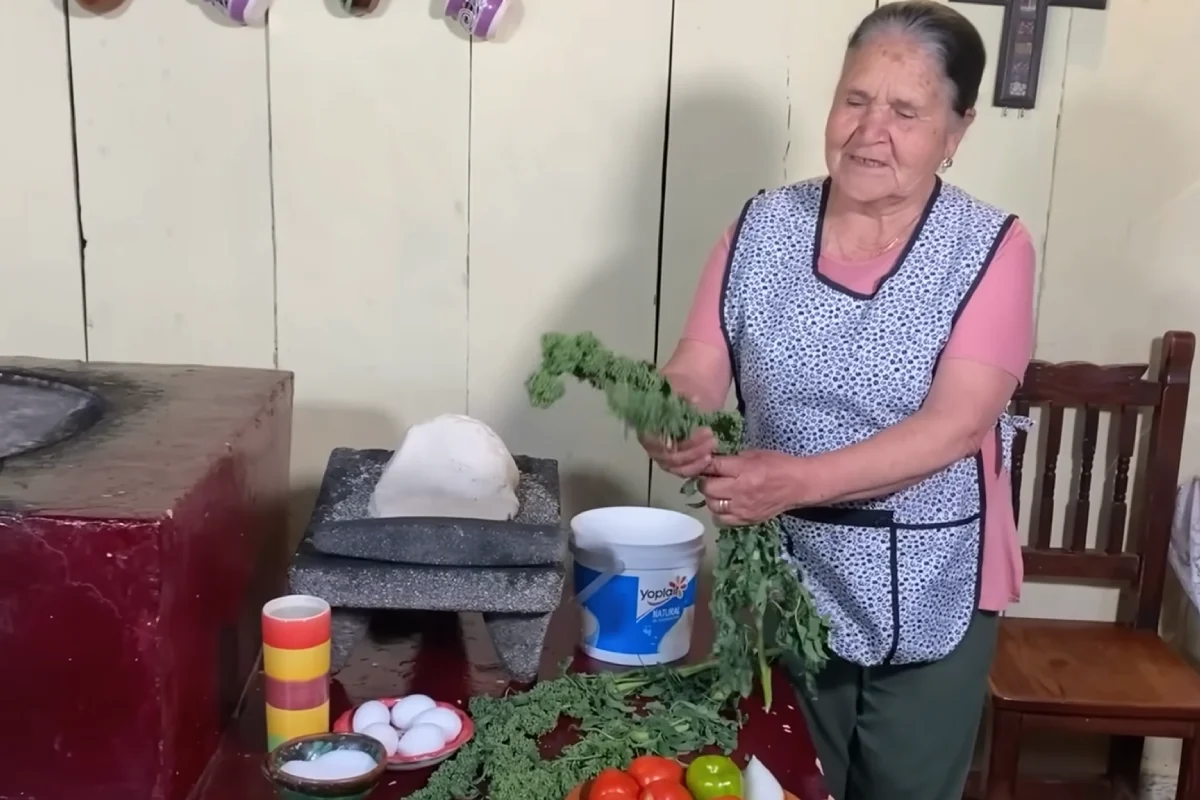 Una mujer sostiene ramas de huanzontle al interior de su cocina
