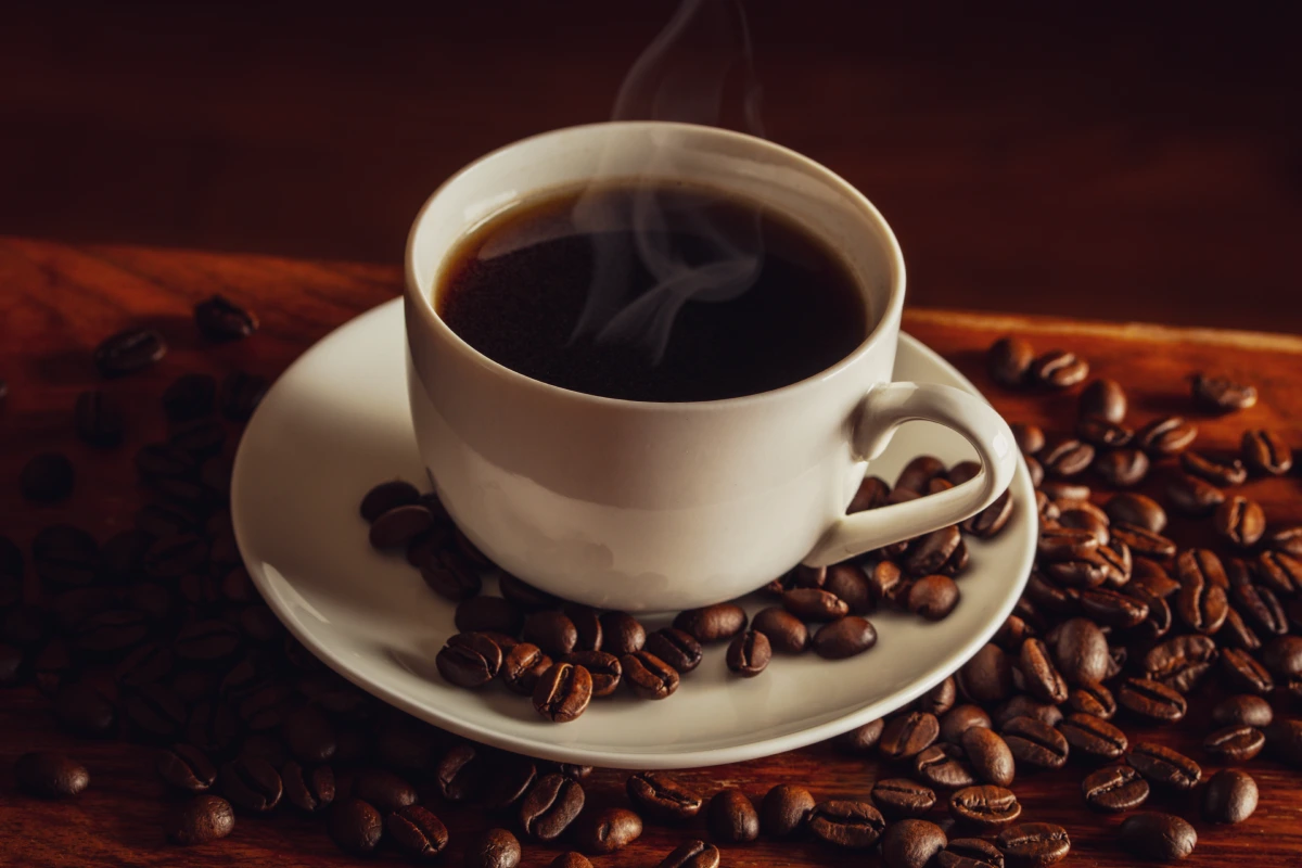 Café caliente y granos de café en la mesa