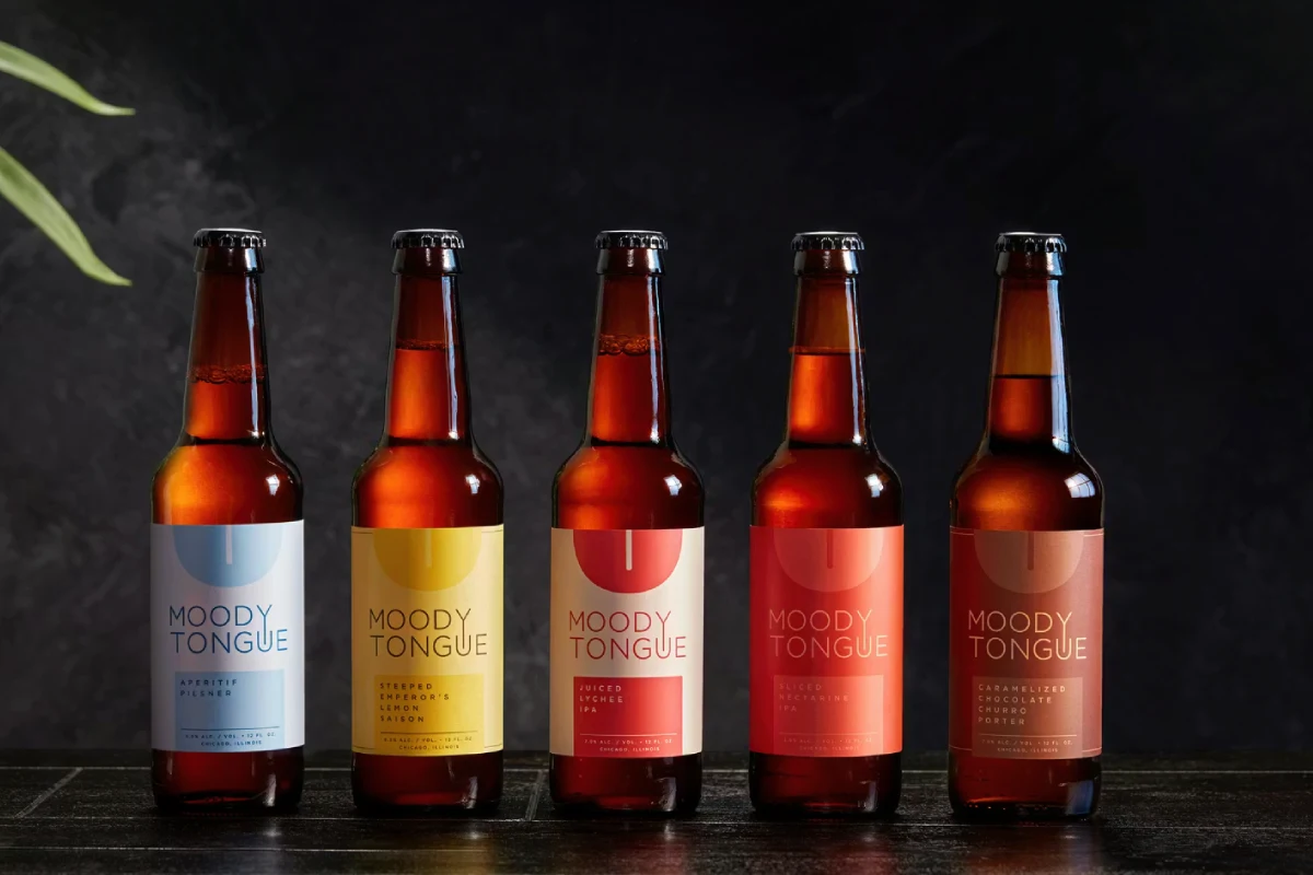 Sobre un fondo negro se encuentran botellas de vidrio con cerveza artesanal
