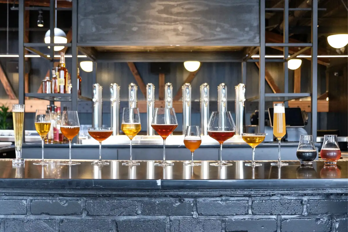Sobre una barra están colocas difetentes tipos de copas con cervezas artesanales