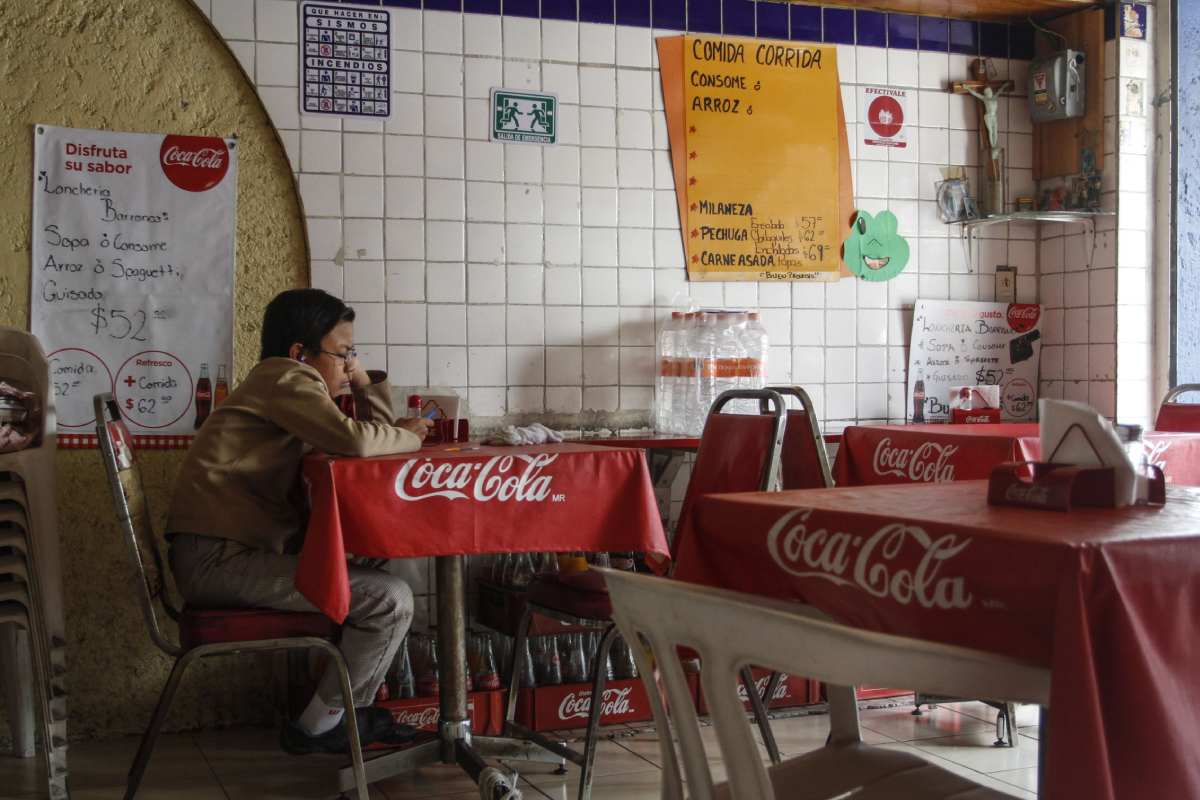 Un estudiante revisa su celular, mientras espera su comida en una fonda de la ciudad de México