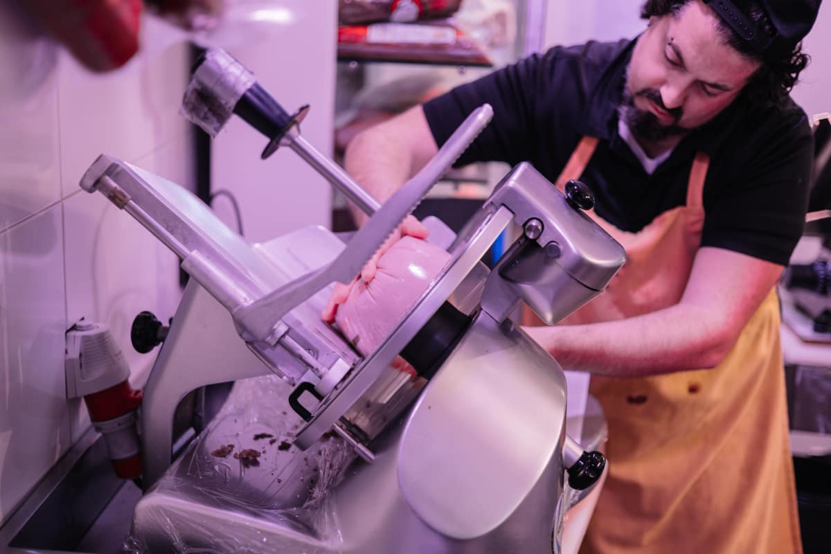 Persona rebanando jamón.