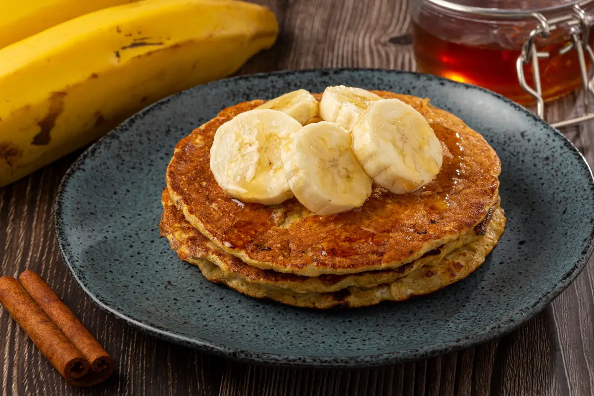 Sobre un platano están servidos pancakes con rodajas de plátano arriba
