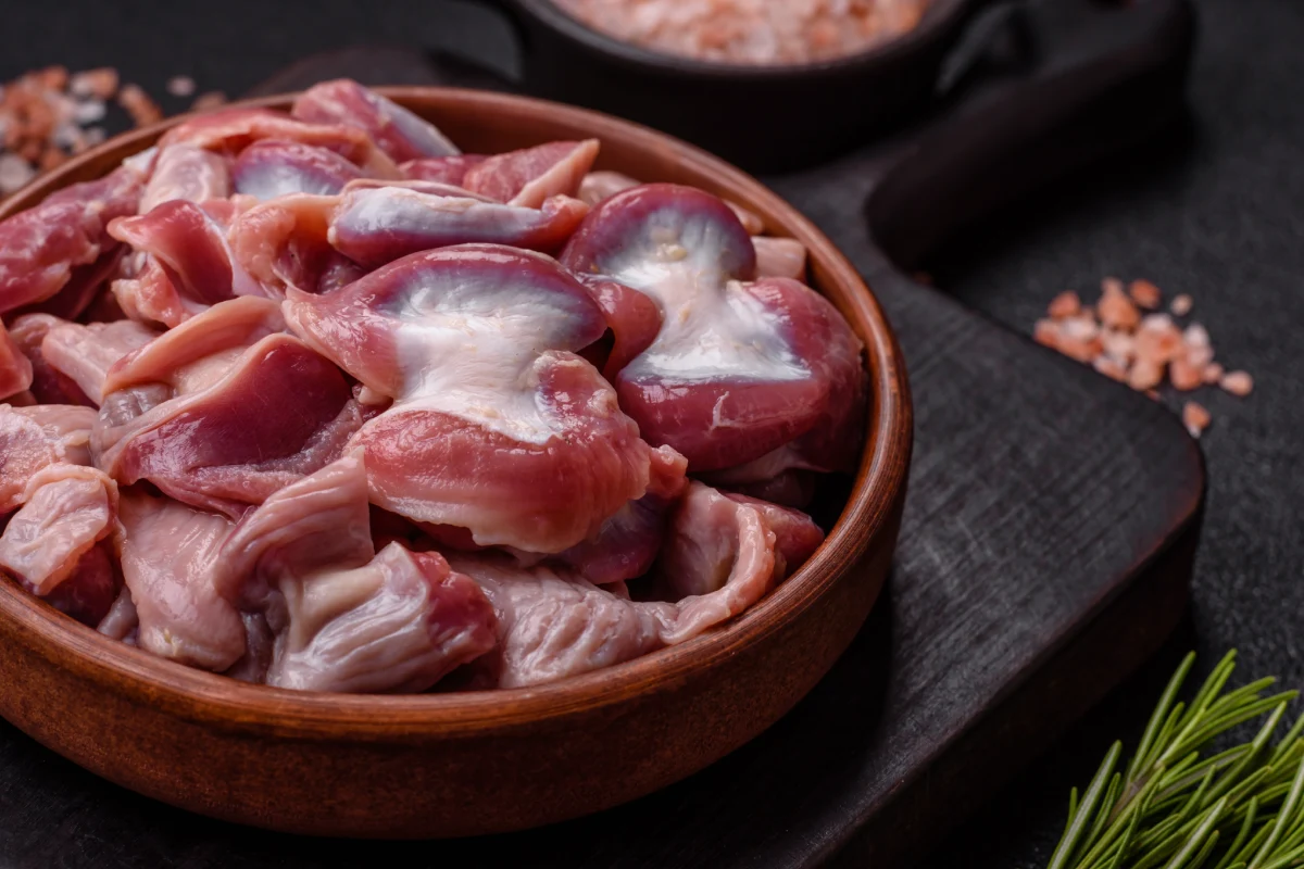 Mollejas crudas de pollo o pavo con sal, especias y hierbas sobre un fondo de hormigón texturizado