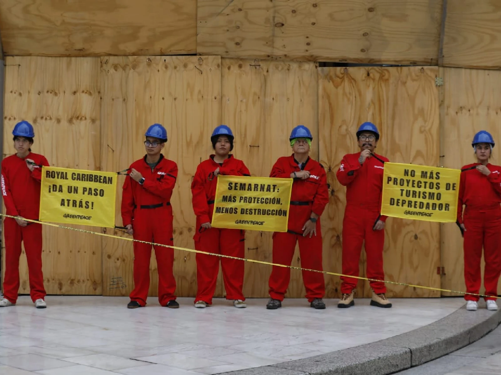 Activistas con overol rojo y con carteles en contra del proyecto perfect day en las escaleras del palacio de bellas artes