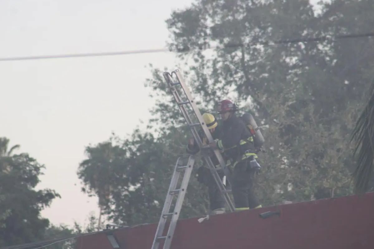 Dos bomberos sobre una escalera trabajando en sofocar el incendio de un casino en Sinaloa. 