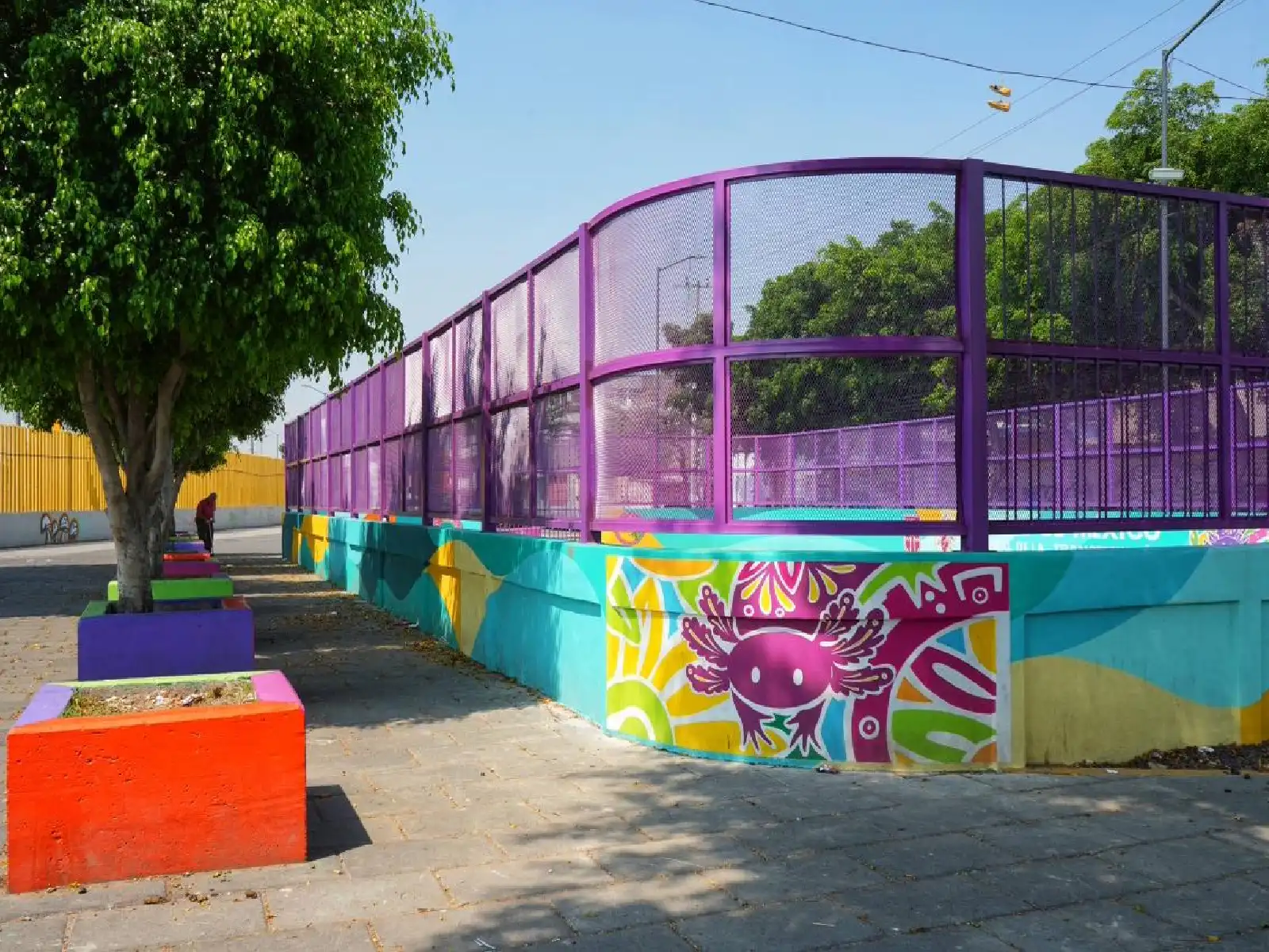 Cancha deportiva con un ajolote pintado en un muro 