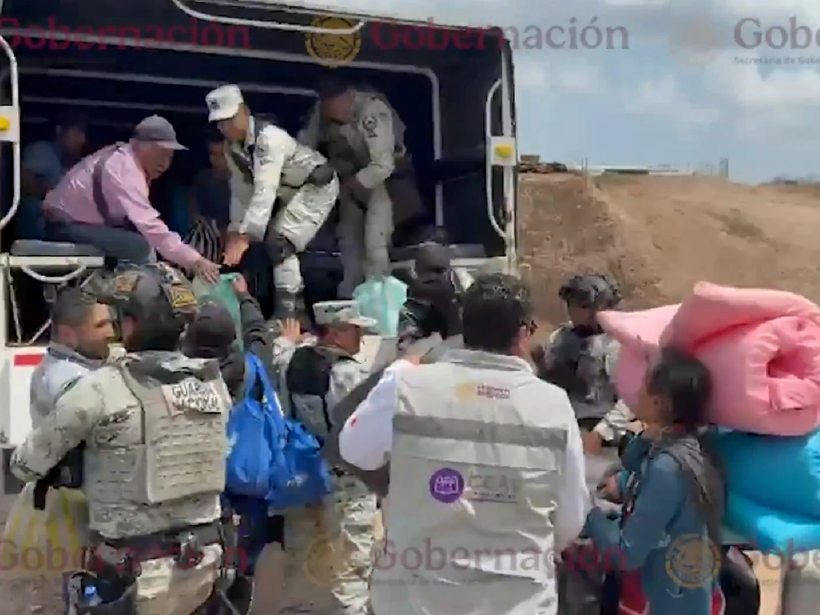 Autoridades de gobierno ayudan a familias de Chilapa, Guerrero a subir a una camioneta para regresar a sus hogares.