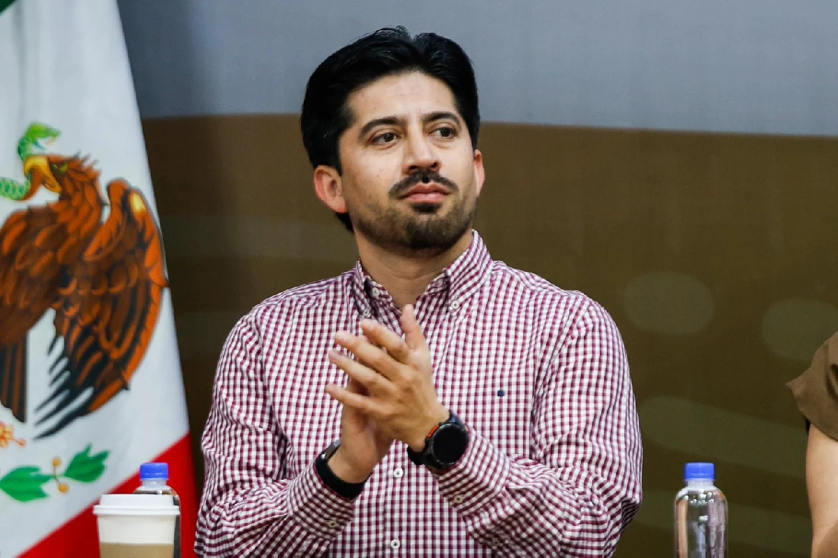 Omar López Campos aplaudiendo y vistiendo una camisa a cuadros rojos con blanco