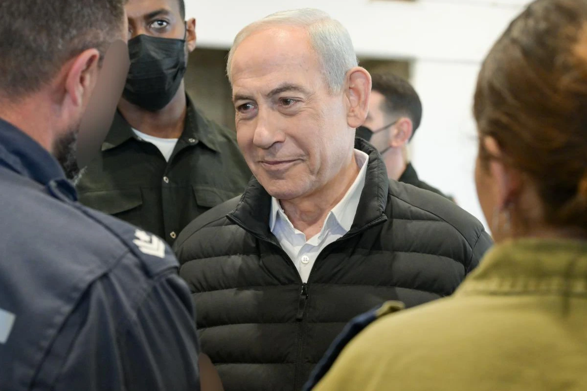 Primer minsitro de Israel con chamarra negra saludando a dos personas
