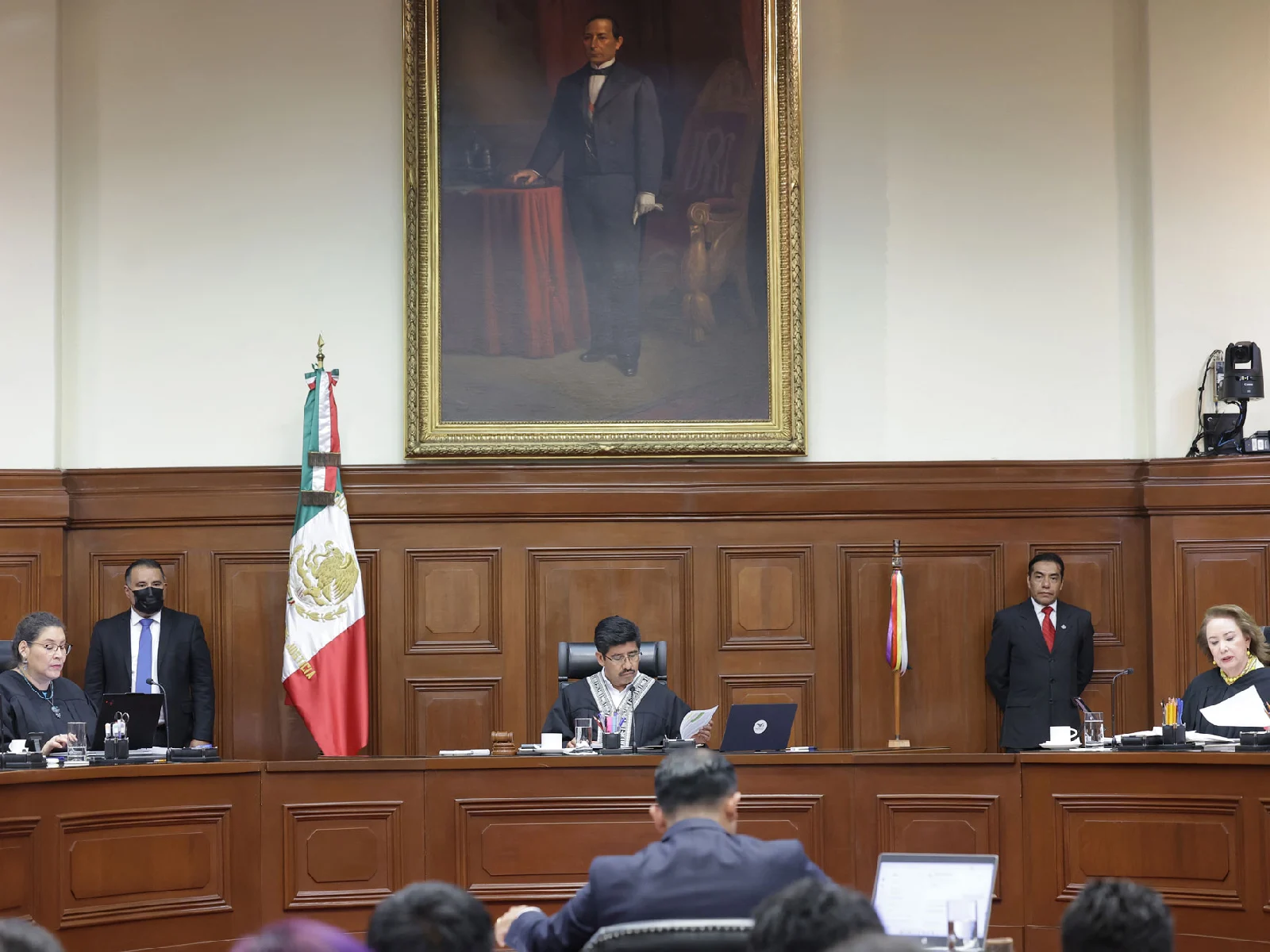 Ministros de la Suprema Corte de Justicia de la Nacion durante sesion en el pleno, con un cuadro de Benito Juárez sobre el ministro presidente. 