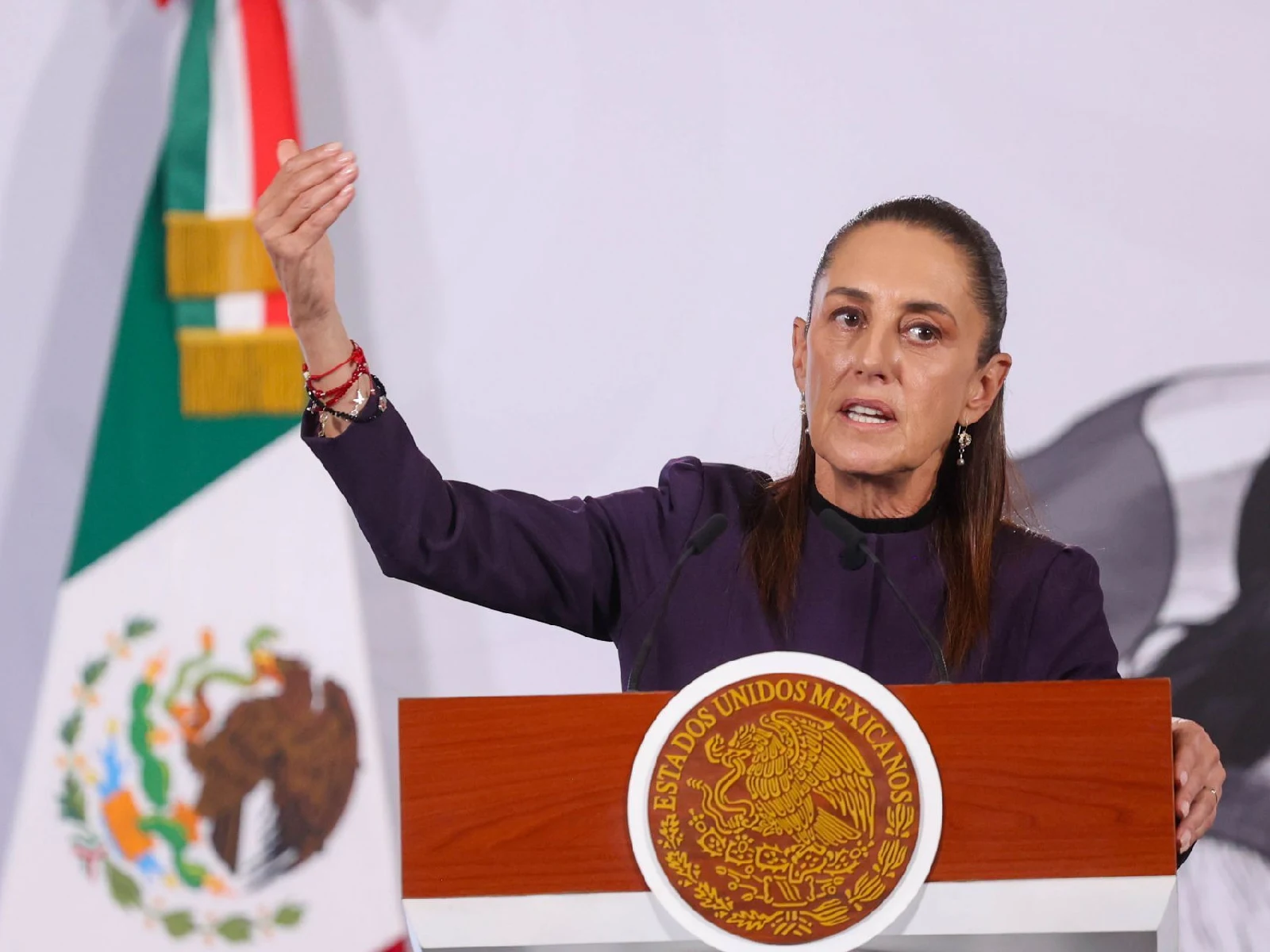 Presidenta Claudia Sheinbaum durante la conferencia de prensa con el brazo levantado y la mirada al frente 