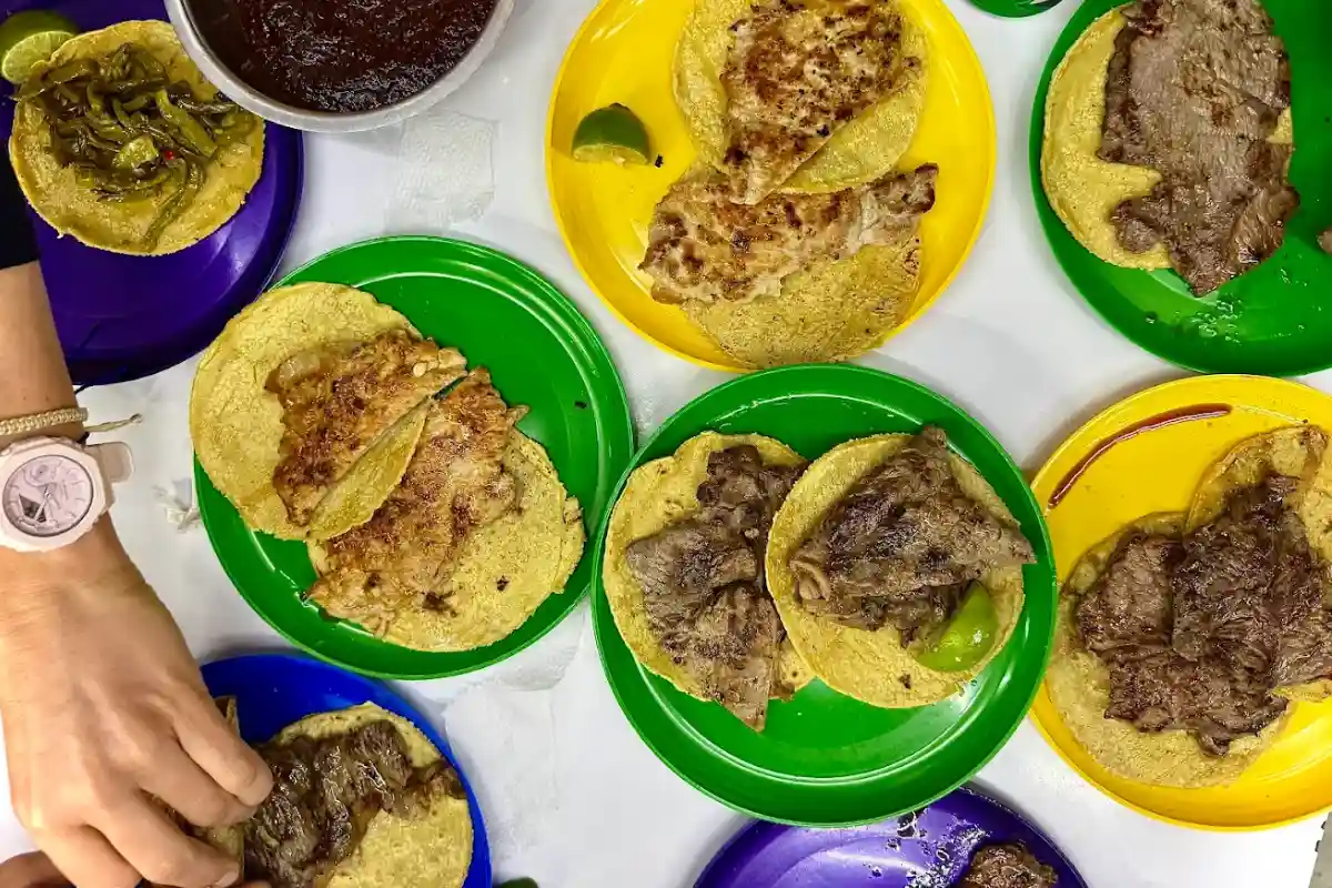 Una mesa con platos de colores con tacos de diferentes carnes