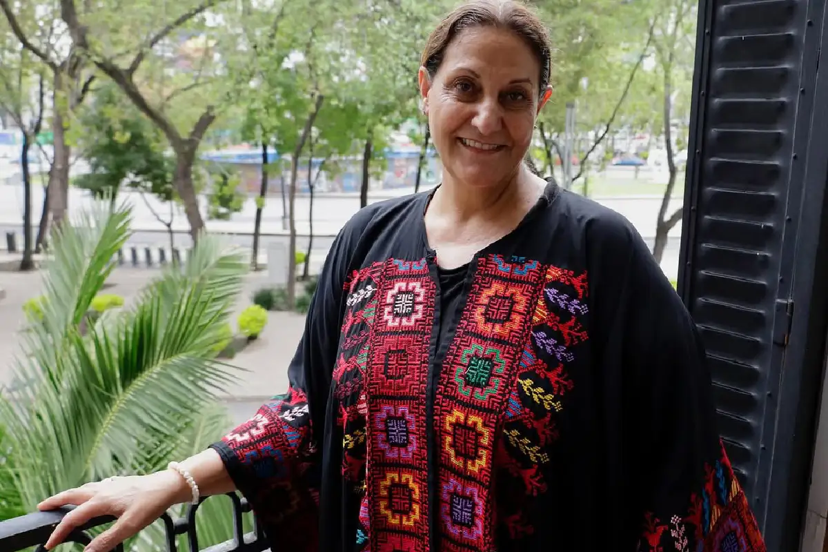 Mujer sonriente porta un bordado palestino 