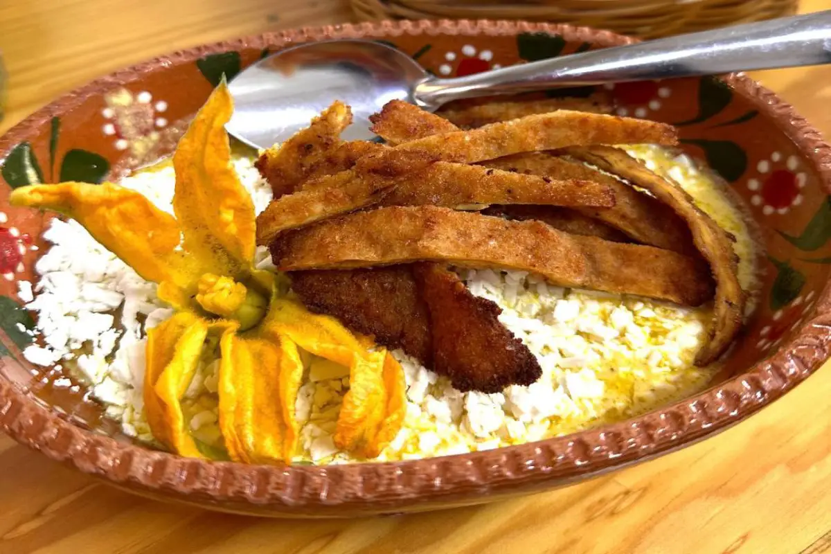 Chilaquiles rellenos en salsa de flor de calabaza con tiras de pechuga empanizada.