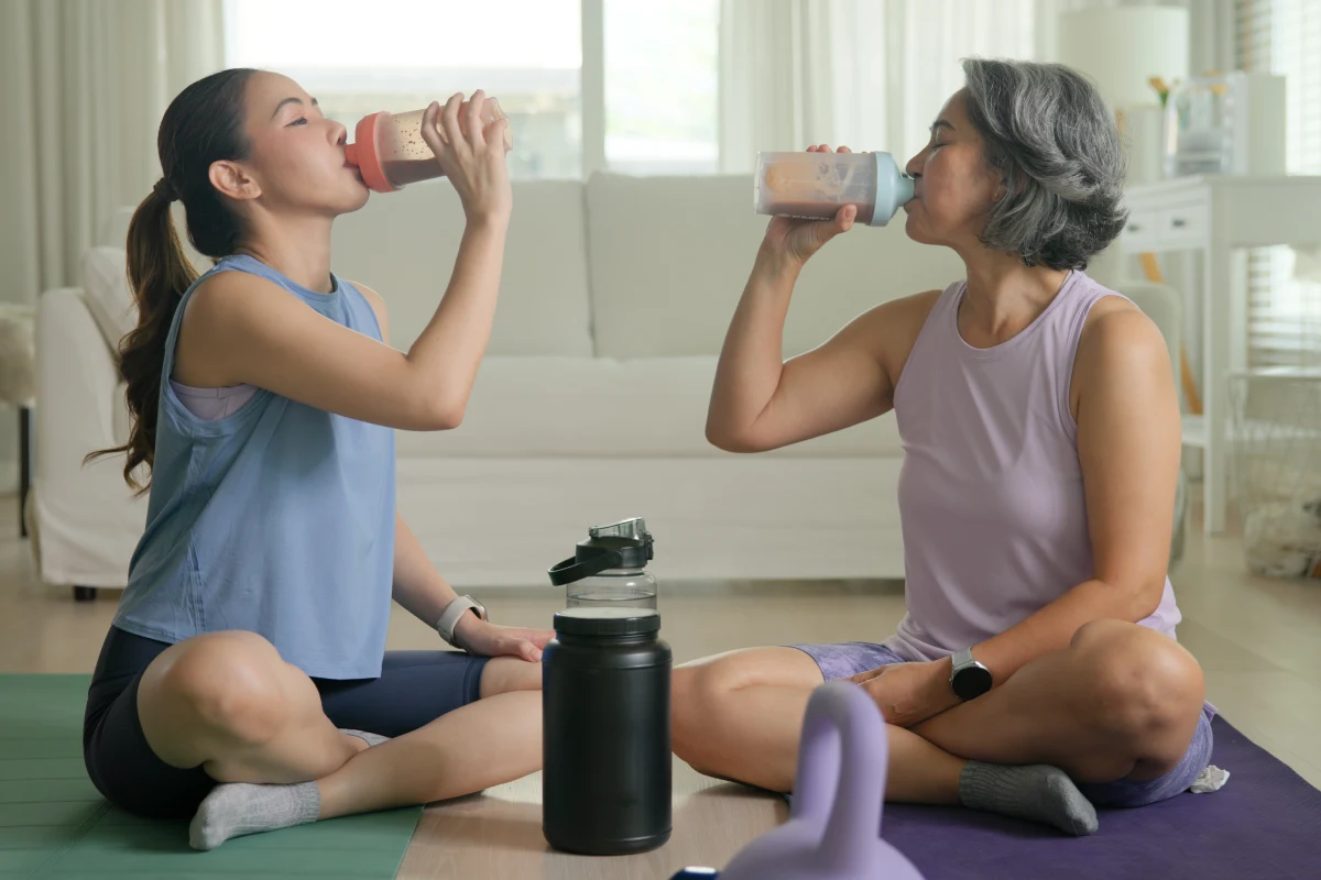 Dos mujeres sentadas toman un batido después de una rutina de ejercicio