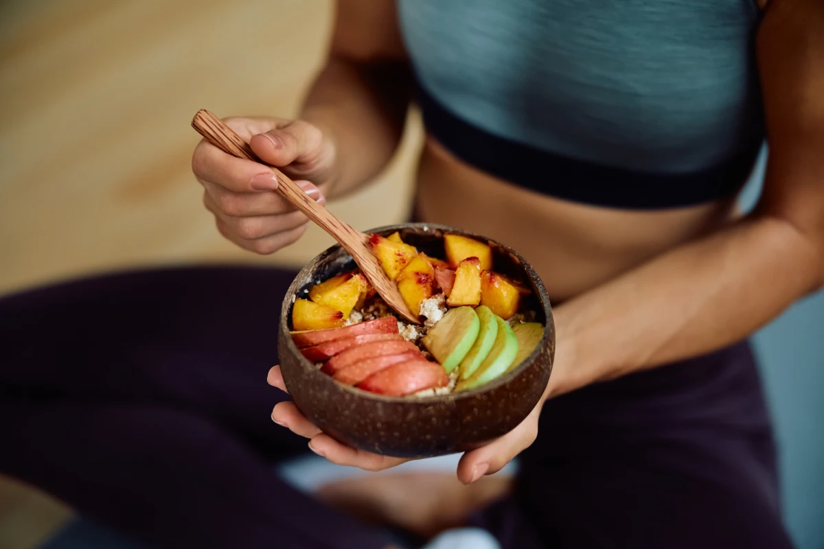 Mujer sostiene un tazón con frutas y verduras