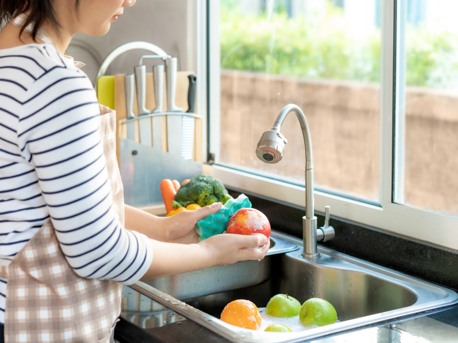Mujer lava con agua y jabón diferentes frutas