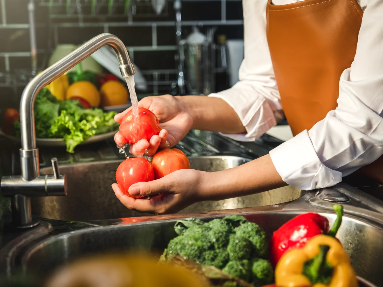 Mano de criada lavando tomate preparación de verduras frescas comida saludable en la cocina