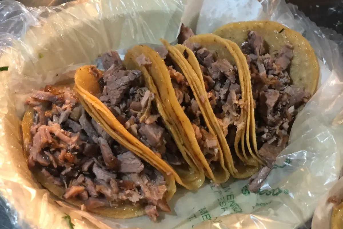 cinco tacos de suadero en un plato cubierto con plástico