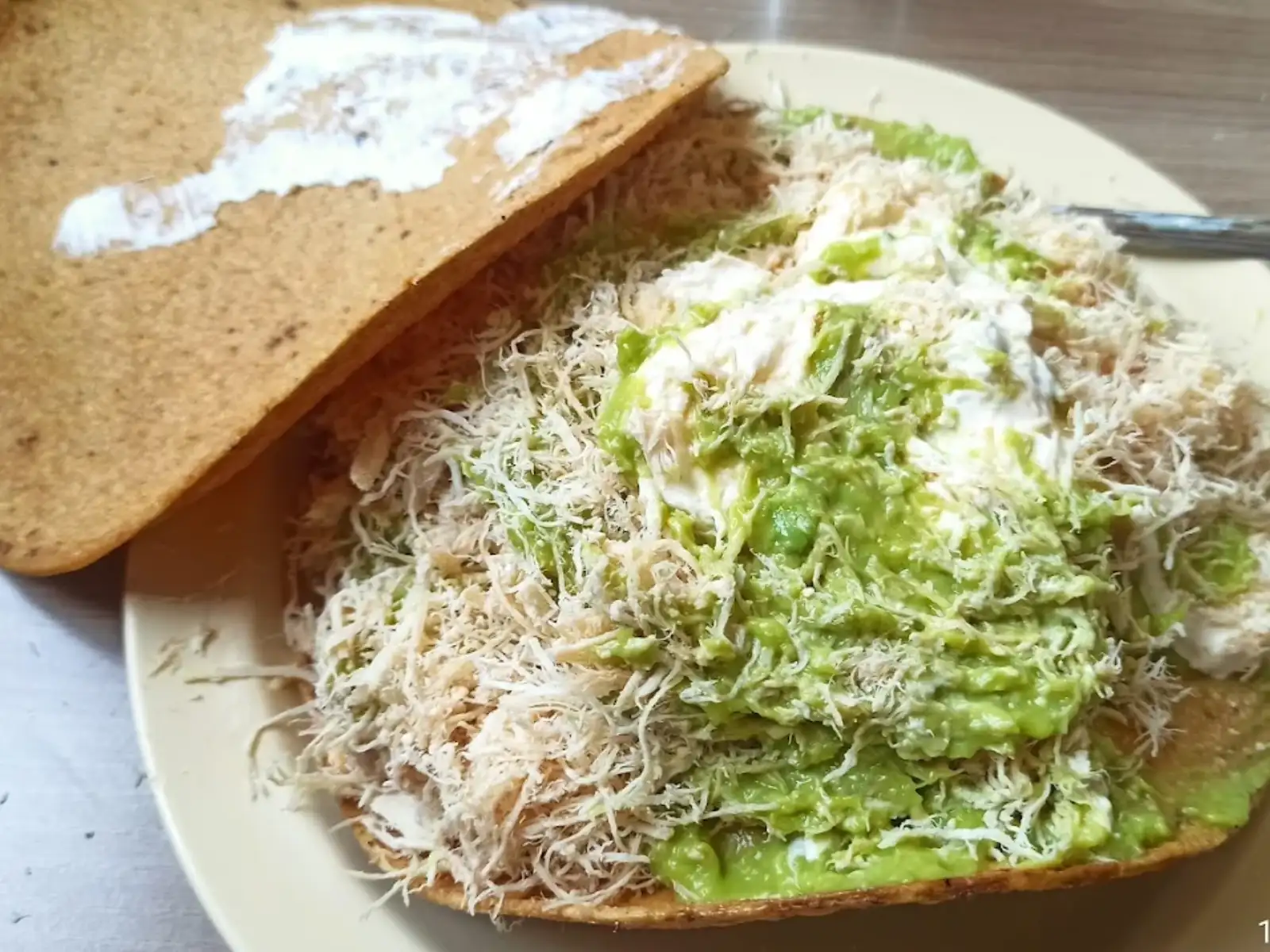 Acercamiento del interior de una tostada con aguacate y pollo