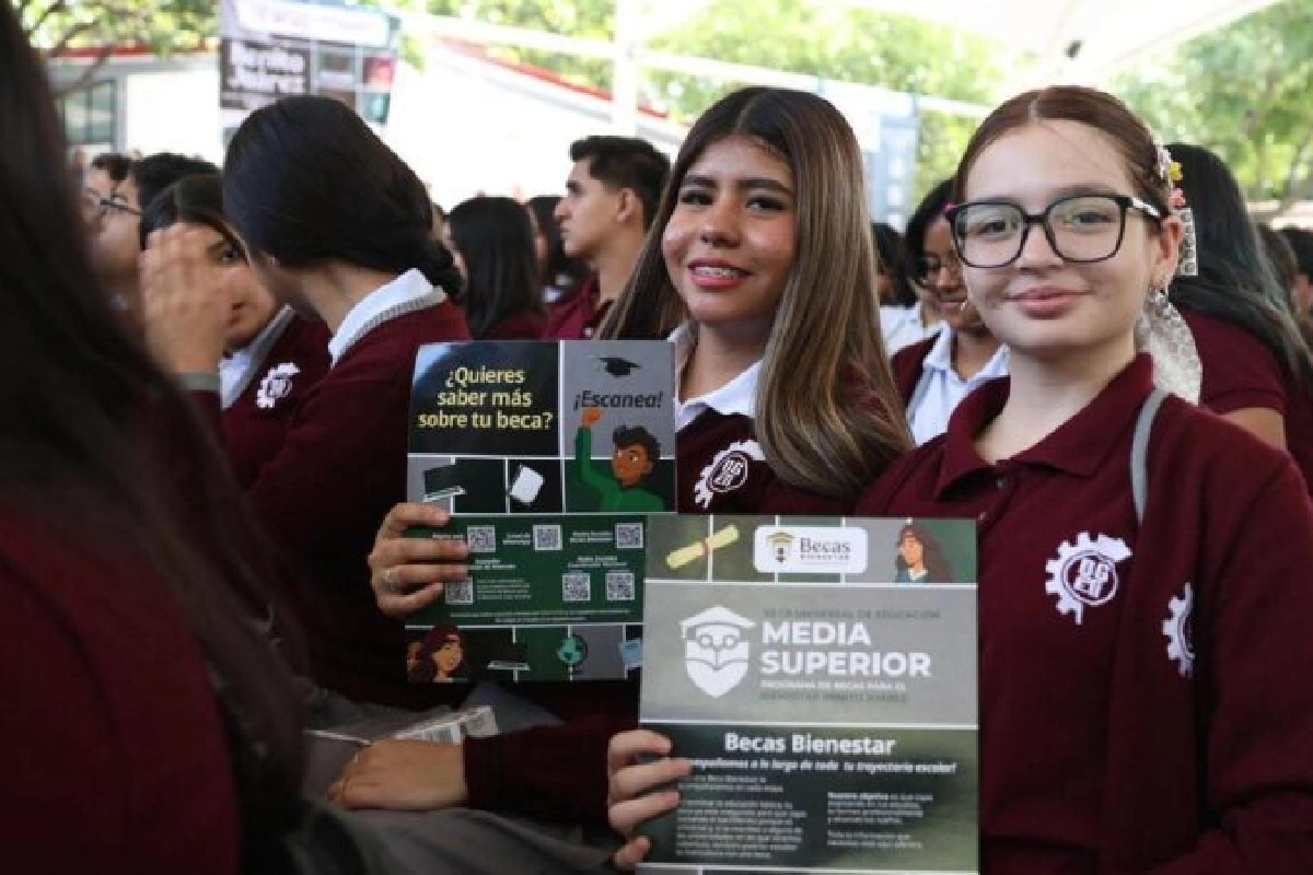 Jóvenes de bachillerato sonriendo mientras sostienen folletos informativos de la beca Benito Juárez