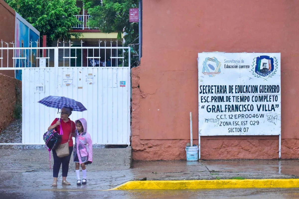 Un niña y su mama afuera de la escuela mientras lluve