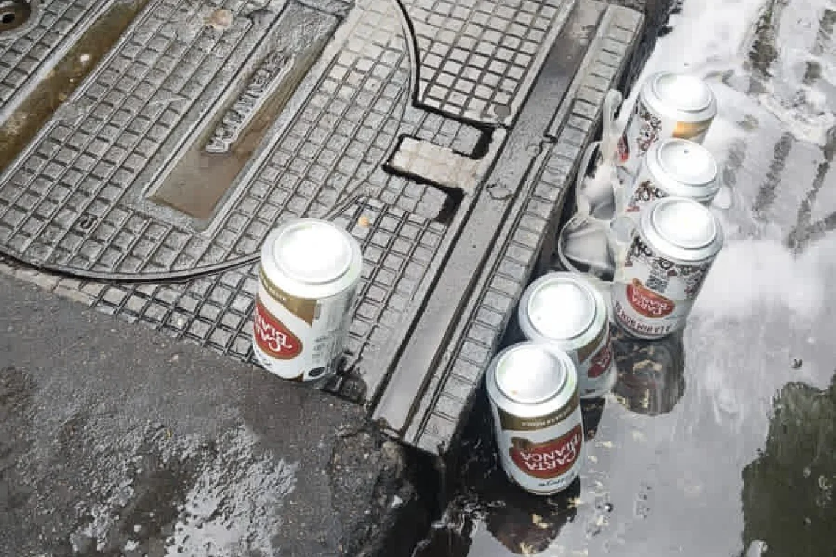 Latas de cerveza volteadas para que derramen su contenido en una coladera del centro históric 