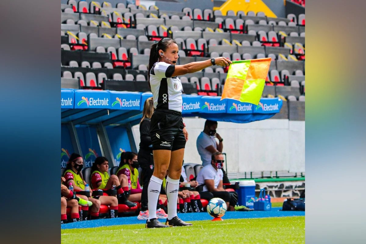 Sandra Elizabeth Ramírez Alemán arbitrando desde la banda de una cancha de futbol