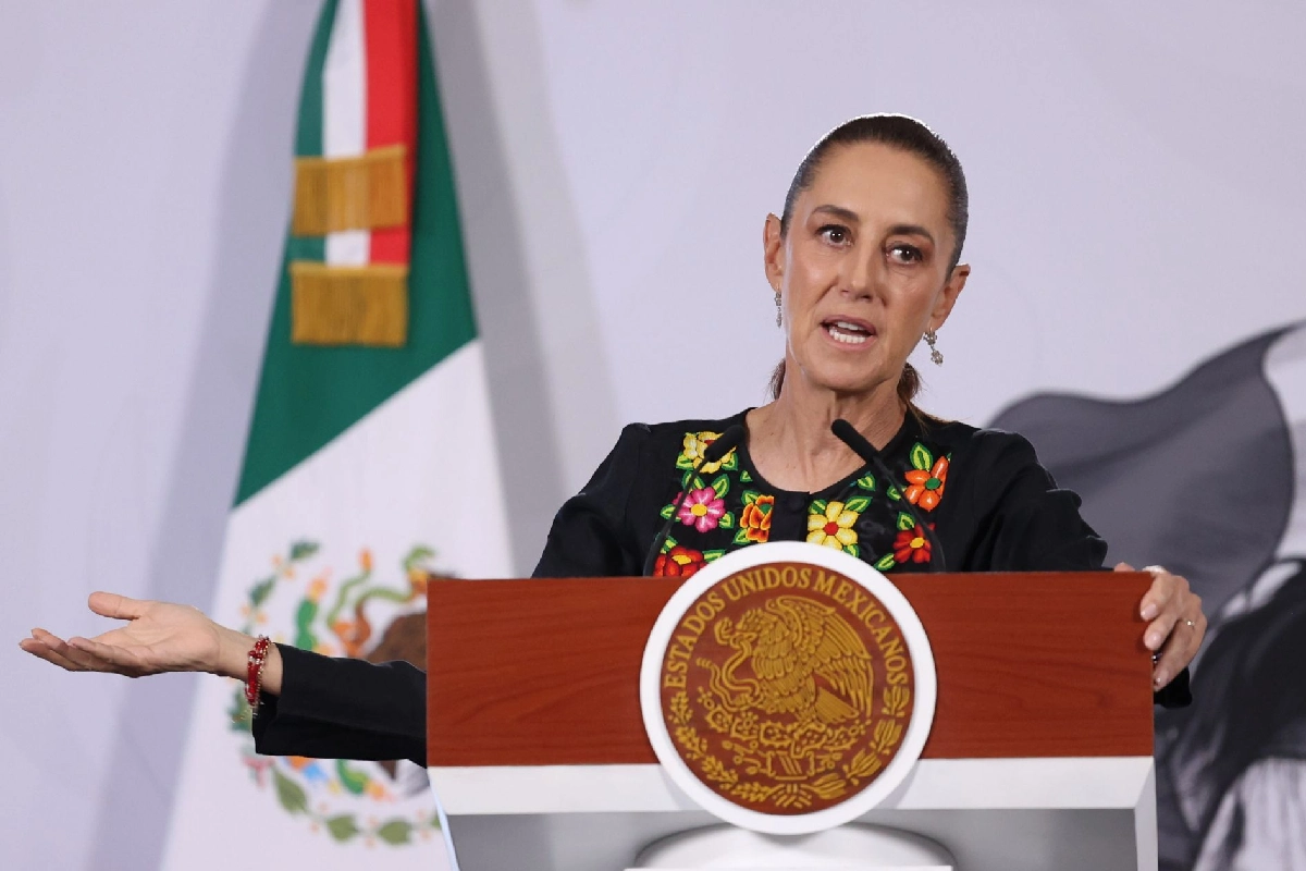 Sheinbaum con el brazo parcialmente estirado con la palma hacia arriba en seña de duda o razón