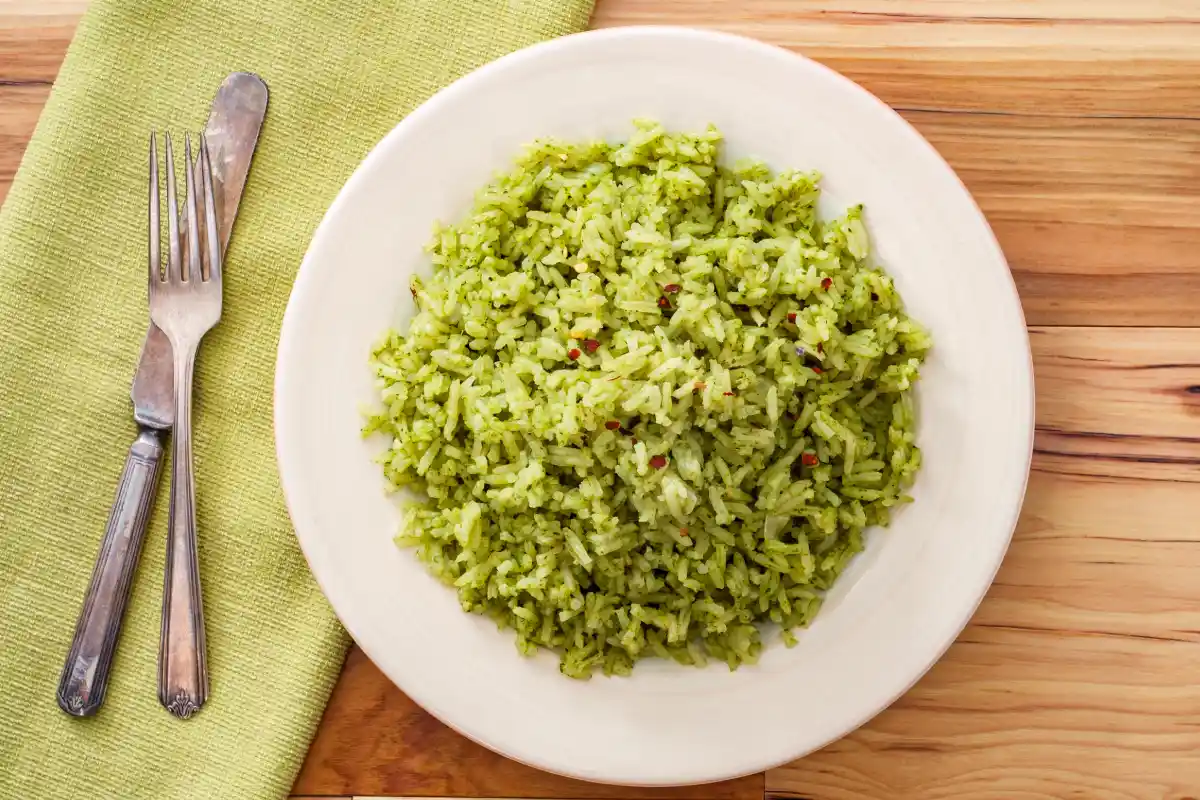 Plato blanco con abundante arroz verde y a un costado unos cubiertos