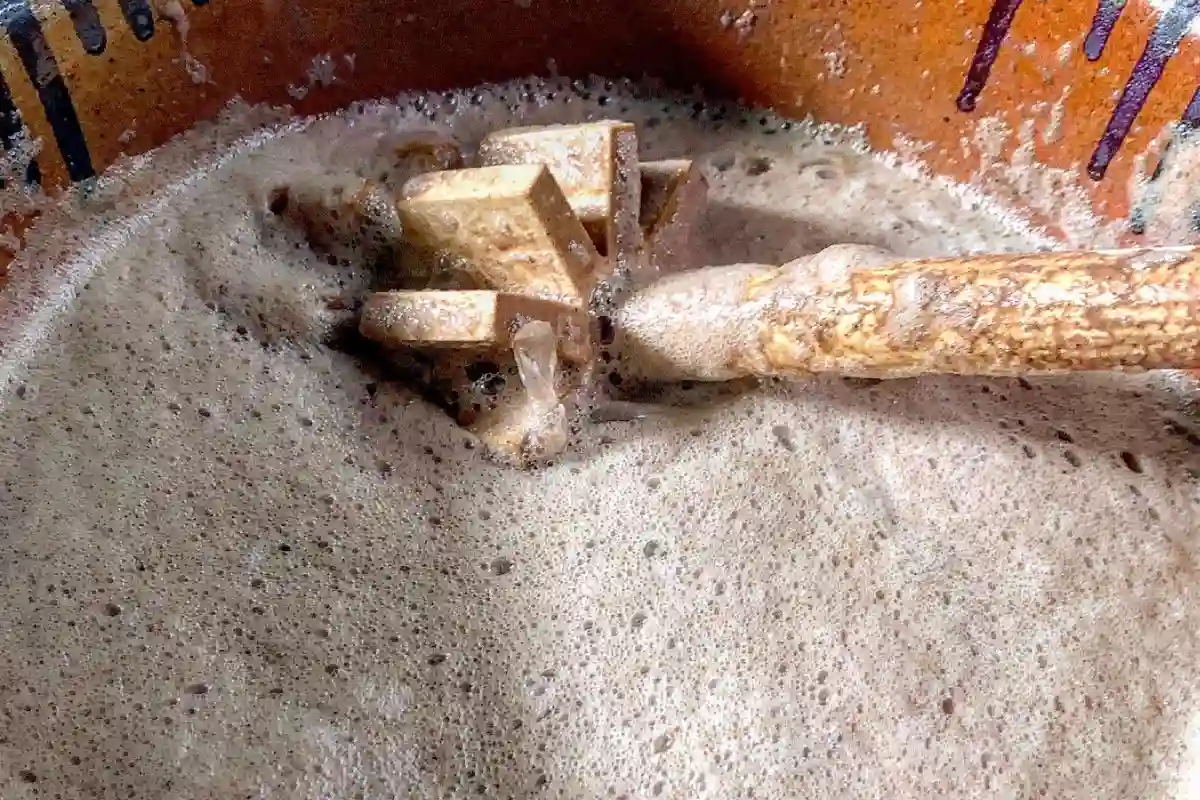 Molinillo de madero al interior de una olla de barro con una agua a base de cacao