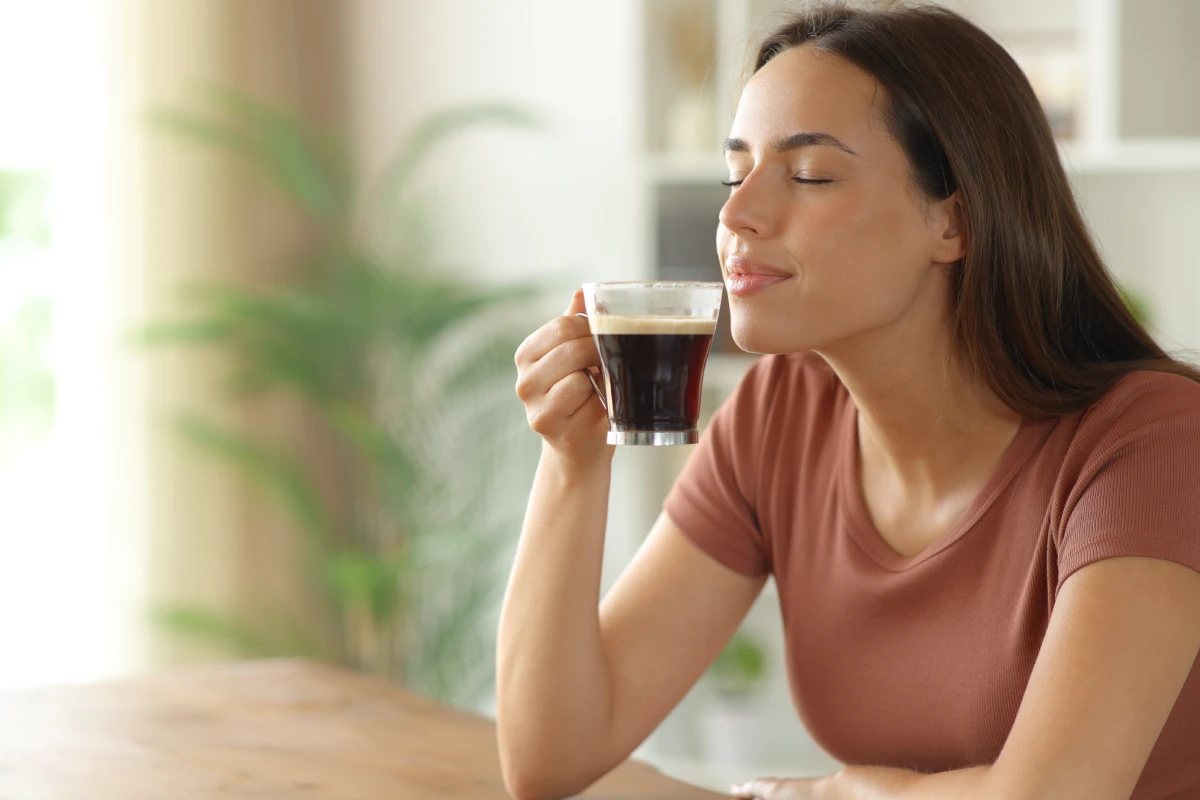 Mujer huele una taza de café