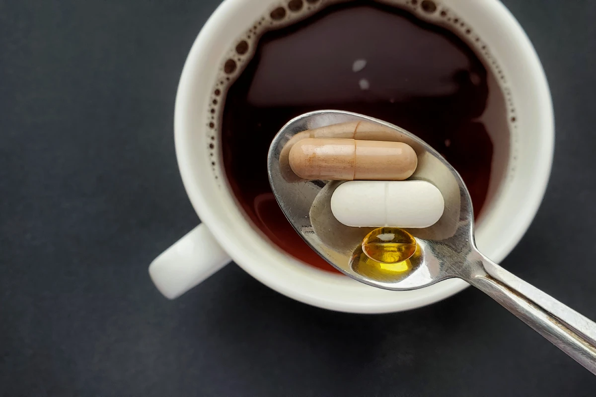 Taza de café con una cuchara que contiene tres pastillas