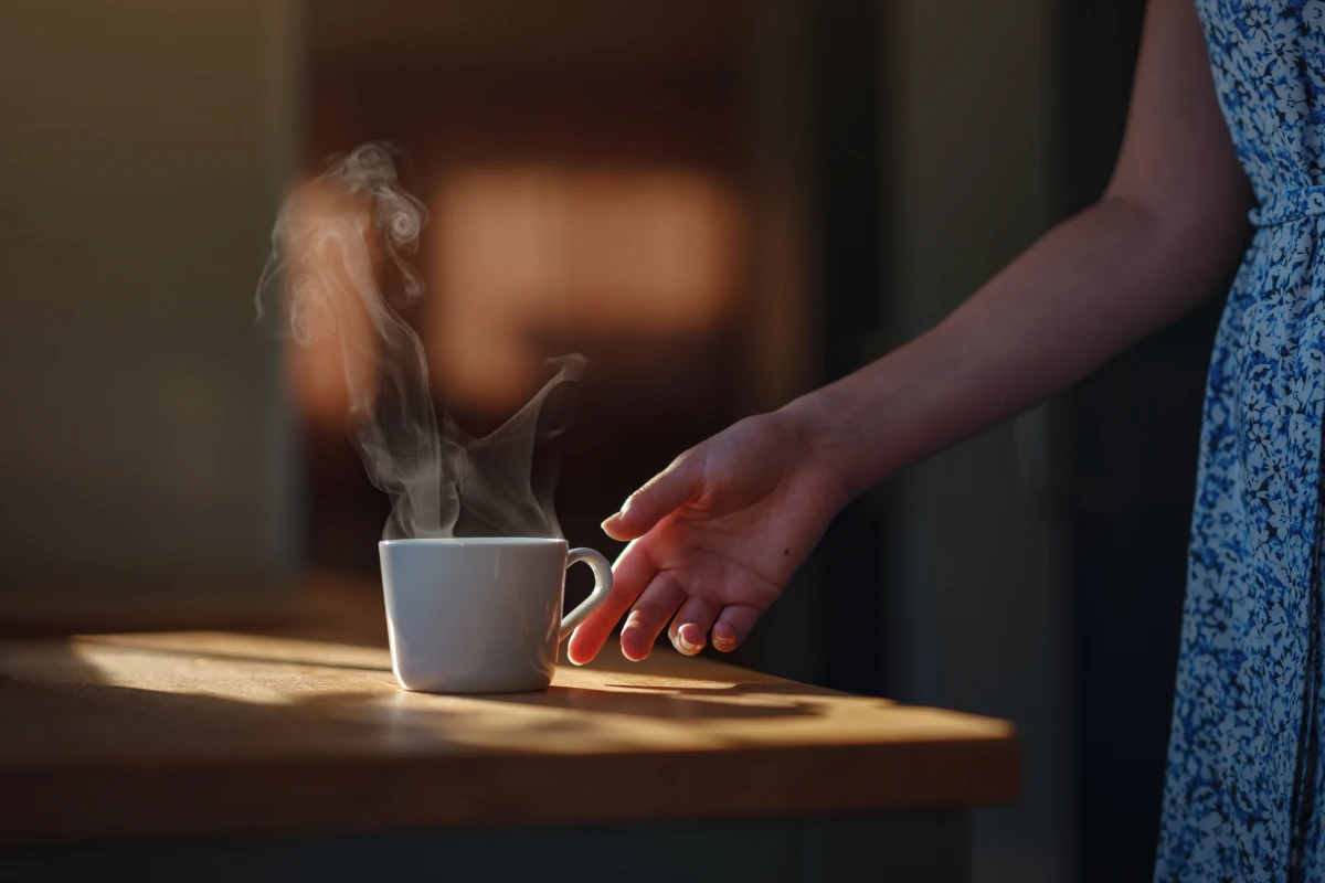 Mujer agarra una taza blanca con café