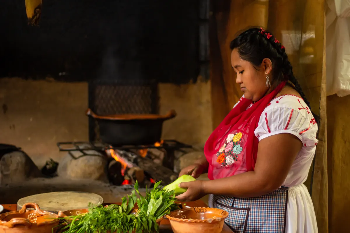 Mujer limpia un chayote en una cocina tradicional mexicana