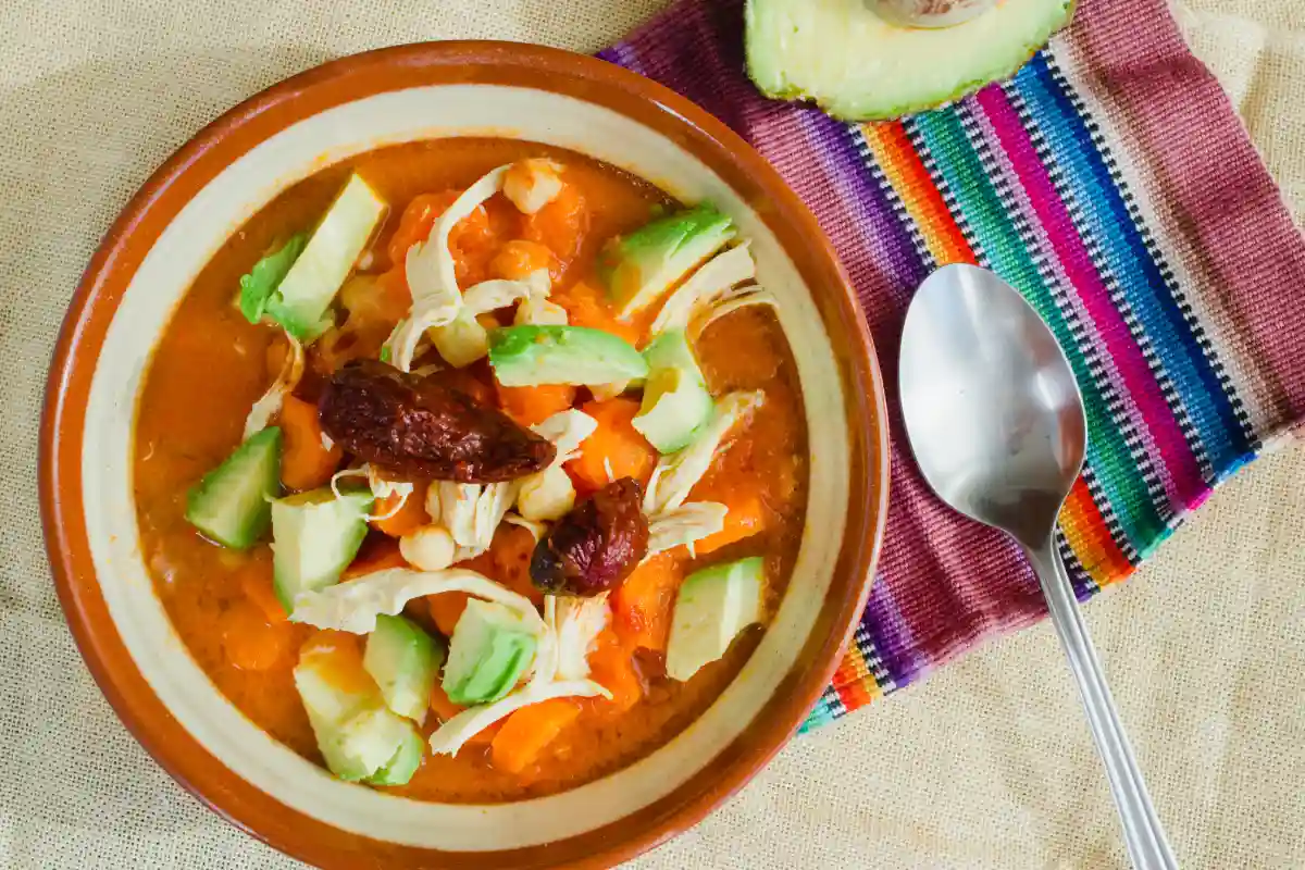 Vista panoramica del caldo tlalpeño servido con zanahoria, aguacate y pollo