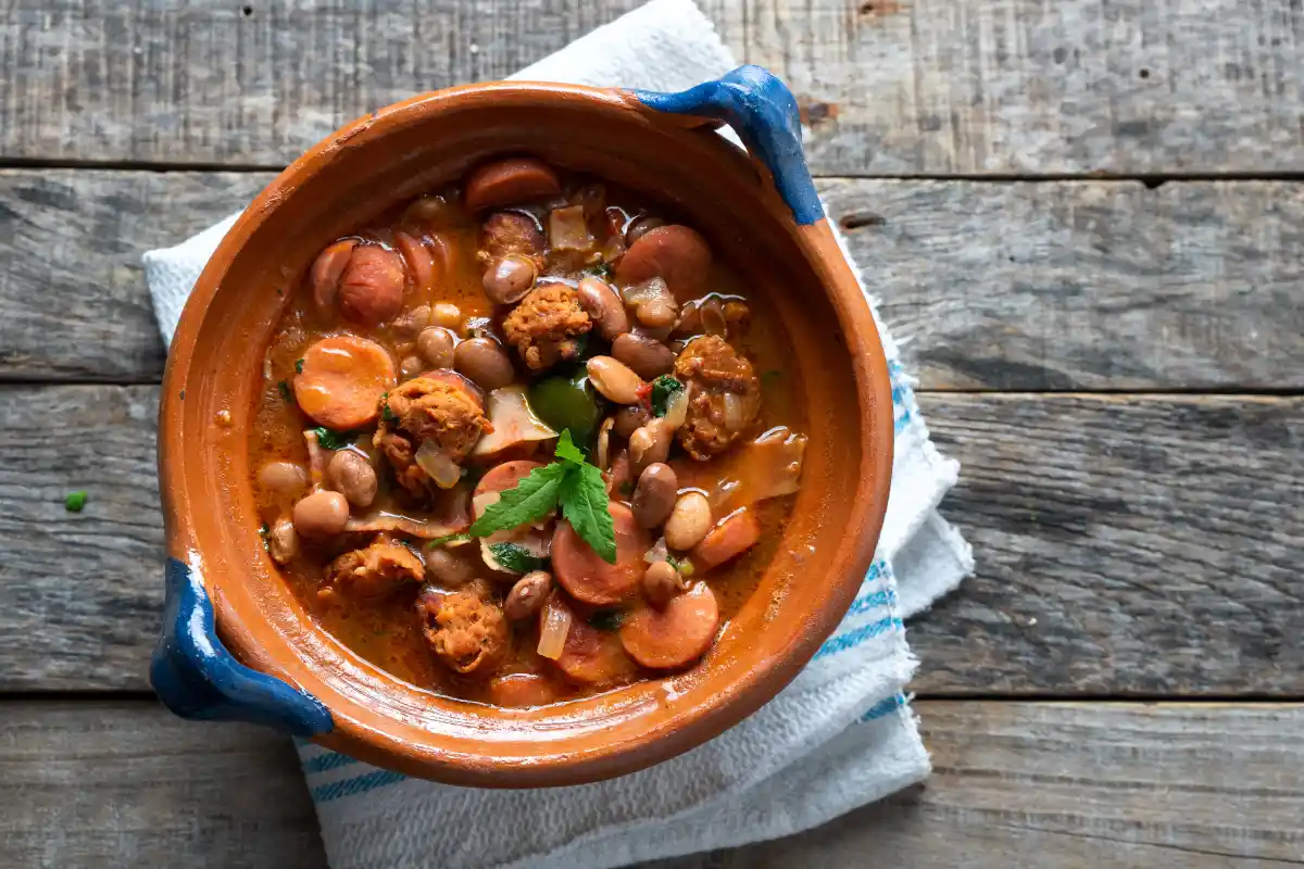 En una pequeña cazuela de barro están servidos frijoles con chorizo y salchicha