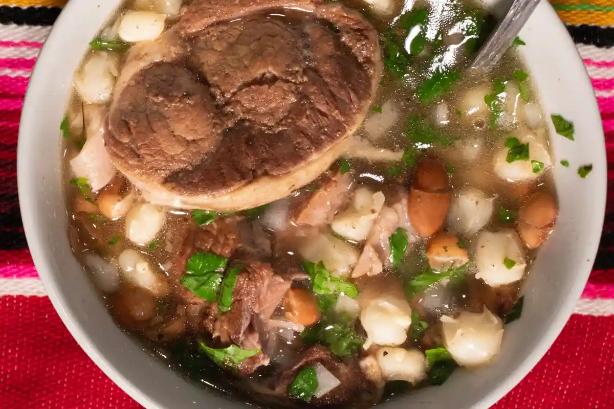 Un plato típico del noroeste de México (Sonora) con maíz y frijoles cocidos, con carne de res en sopa con cilantro y cebolla picada. GALLINA PINTA, sobre un paño de mesa mexicano. Vista superior, formato cuadrado plano