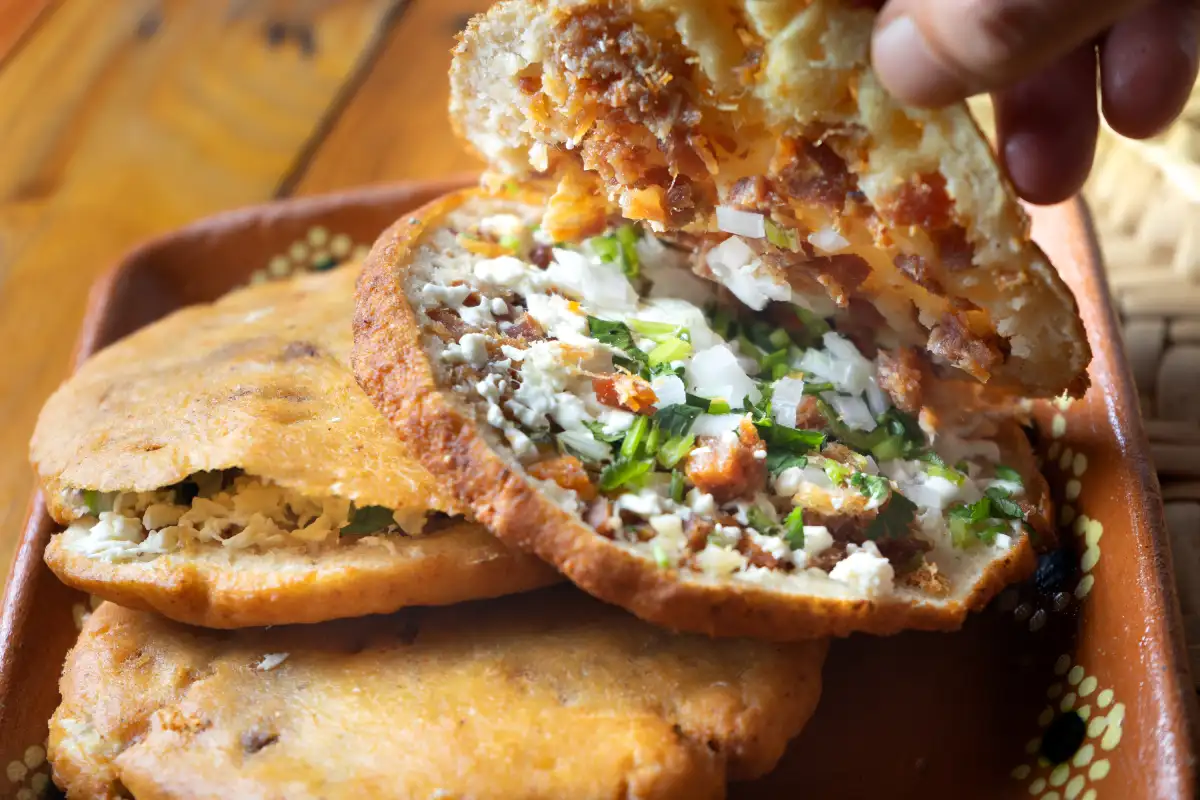 Tres gorditas de chicharrón en un plato de barro, una de ellas está abierta