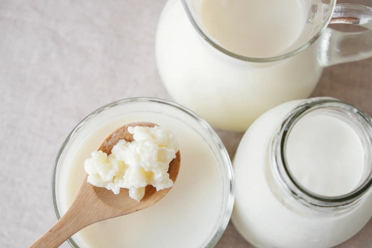Frascos de vidrio y una cuchara de madera con kéfir de leche
