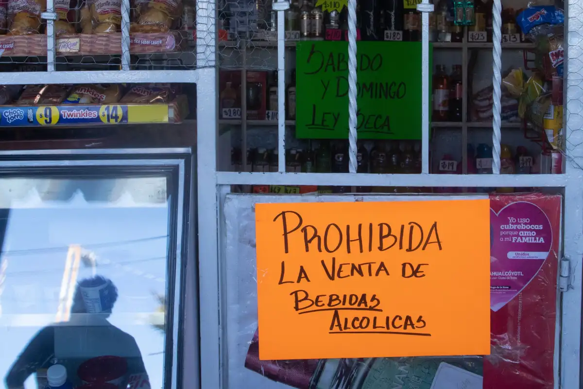 Cartulina anaranjada con un anuncia de prohibicion de venta de bebidas alcoholicas